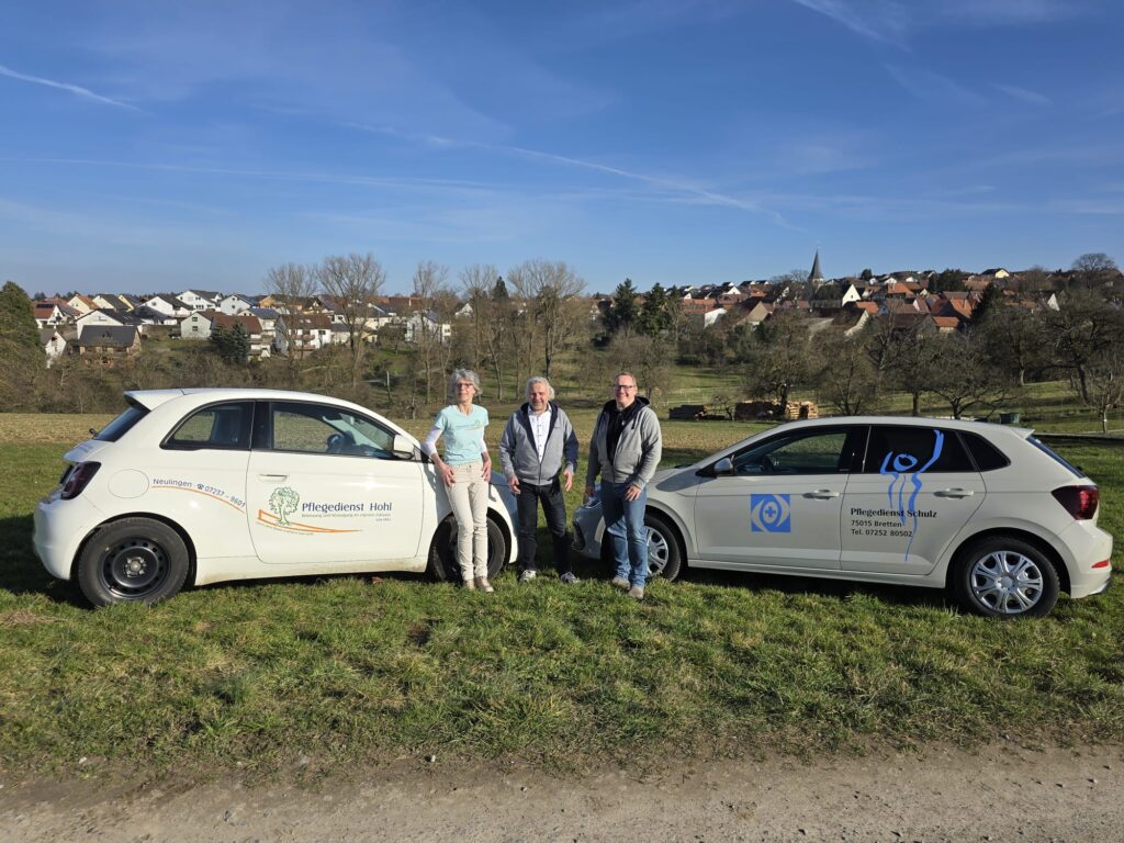 Foto mit einem Auto des Pflegedienst Hohl und einem des Pflegedienst Schulz. Davor stehen die Leitung der beiden Pflegedienste